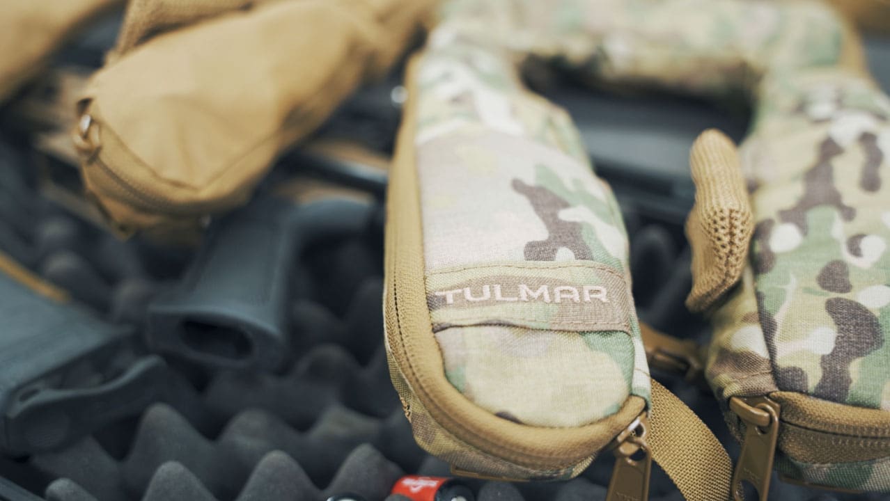 Équipement militaire de camouflage et pièces d'armes à feu sur un fond texturé.