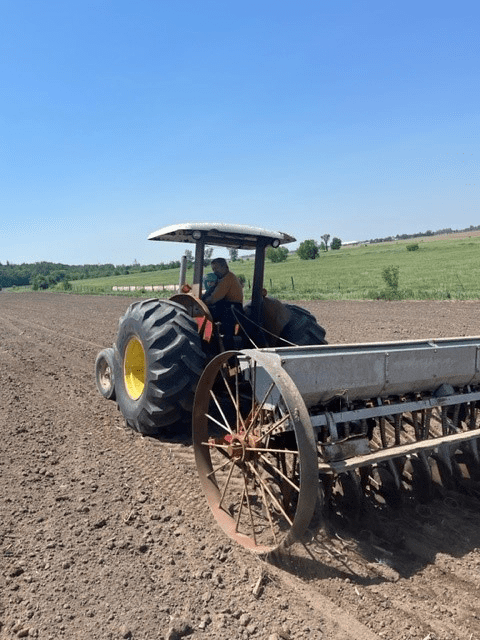 Un tracteur travaillant la terre dans un champ avec un ciel clair en arrière-plan.